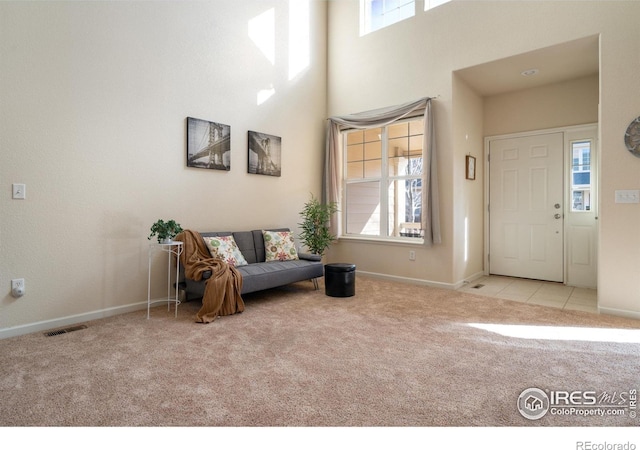 carpeted entrance foyer featuring plenty of natural light, a high ceiling, visible vents, and baseboards