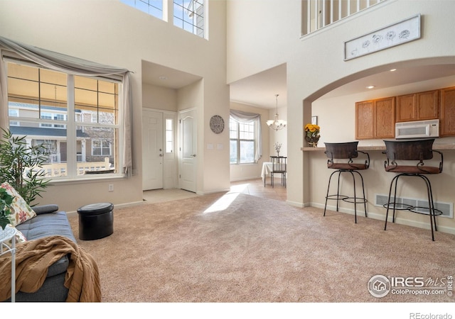 interior space featuring a chandelier, light colored carpet, visible vents, and baseboards