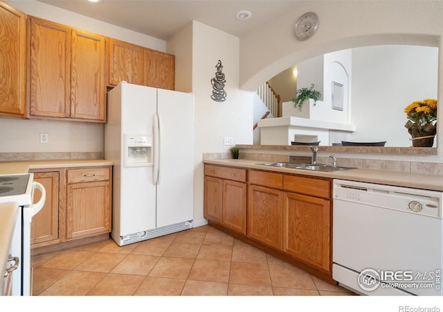 kitchen featuring white appliances, light countertops, a sink, and light tile patterned floors