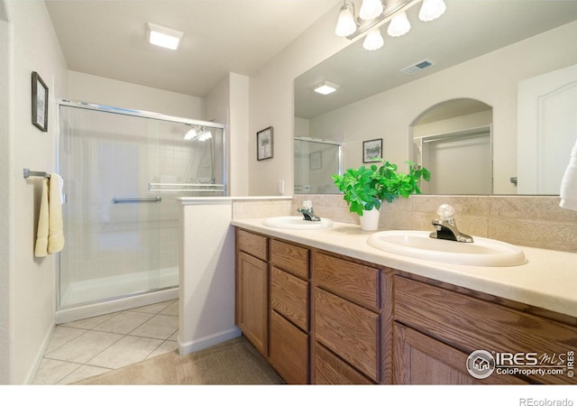 full bathroom with tile patterned flooring, a sink, visible vents, and a shower stall