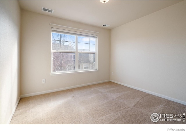 empty room with carpet floors, baseboards, and visible vents