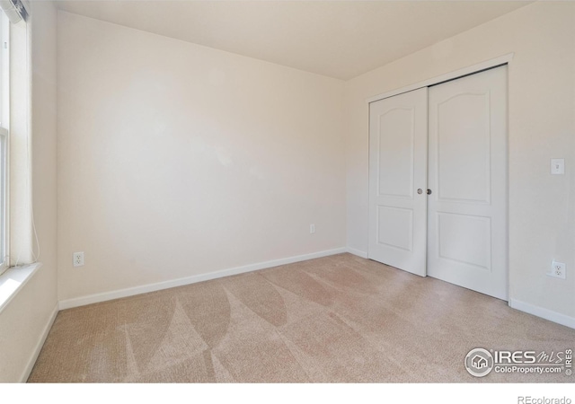 unfurnished bedroom with carpet floors, a closet, and baseboards