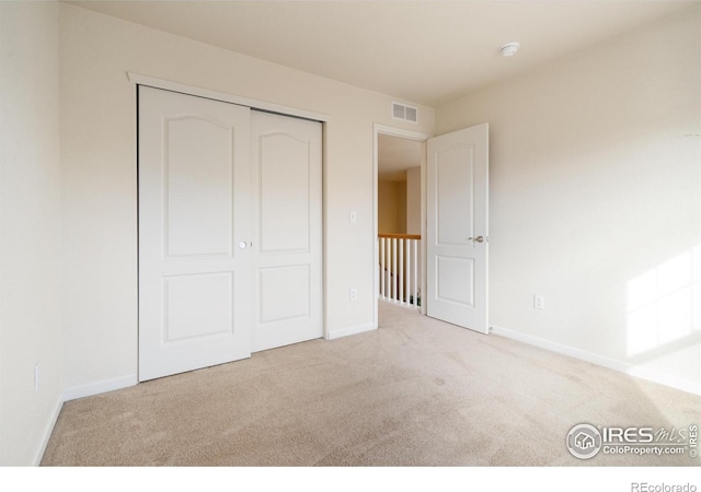 unfurnished bedroom with carpet floors, a closet, visible vents, and baseboards