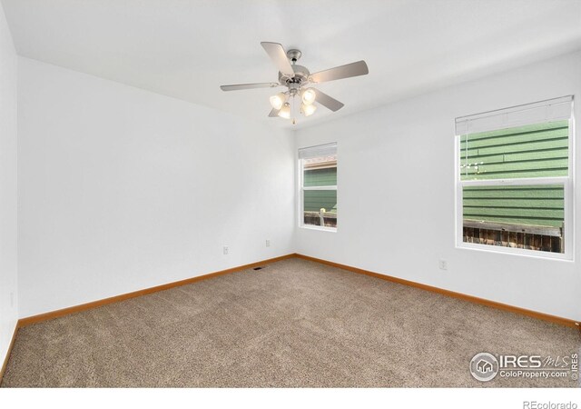 unfurnished room with carpet flooring, a ceiling fan, and baseboards