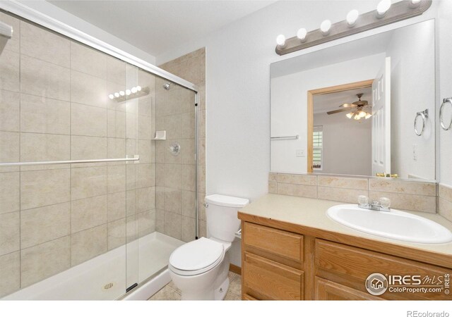 bathroom featuring toilet, a stall shower, a ceiling fan, tasteful backsplash, and vanity