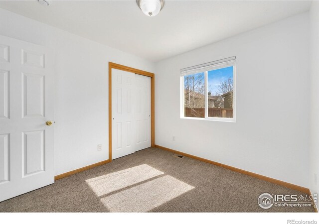 unfurnished bedroom featuring a closet, baseboards, visible vents, and carpet floors