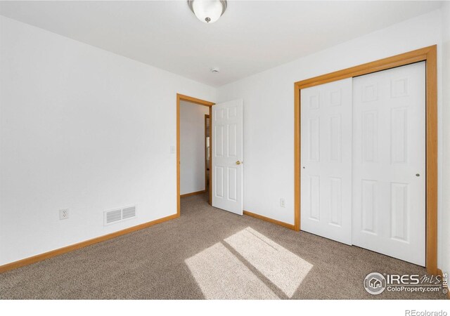 unfurnished bedroom with a closet, baseboards, visible vents, and carpet floors