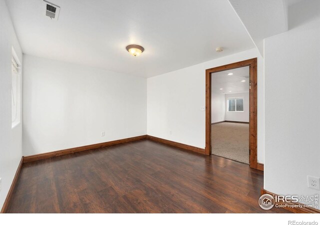 unfurnished room featuring visible vents, baseboards, and dark wood-style floors