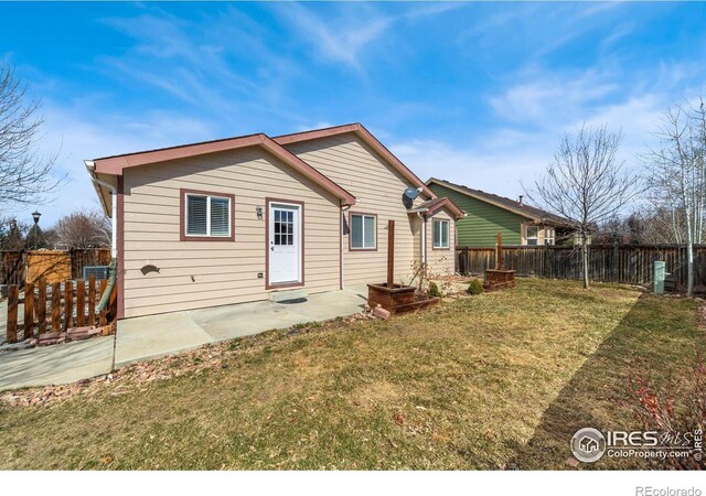 rear view of house with a patio area, a fenced backyard, and a yard