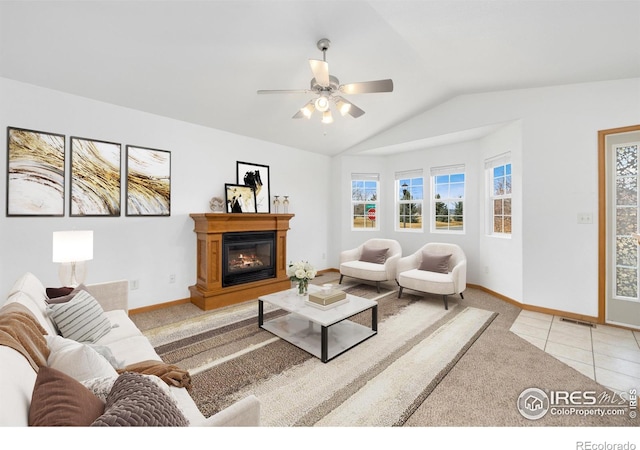 living area featuring baseboards, visible vents, lofted ceiling, light carpet, and a glass covered fireplace