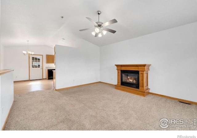 unfurnished living room featuring visible vents, lofted ceiling, light carpet, a glass covered fireplace, and ceiling fan with notable chandelier