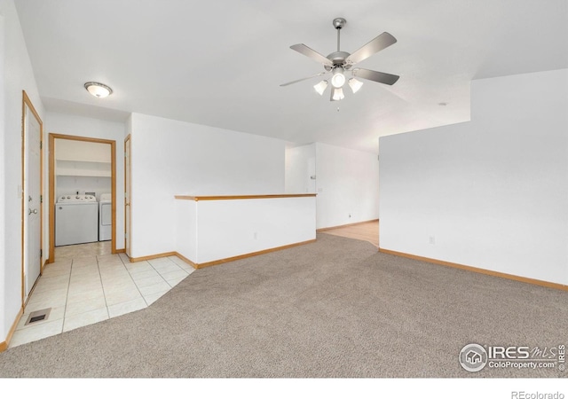 carpeted spare room with washing machine and clothes dryer, visible vents, baseboards, tile patterned floors, and a ceiling fan