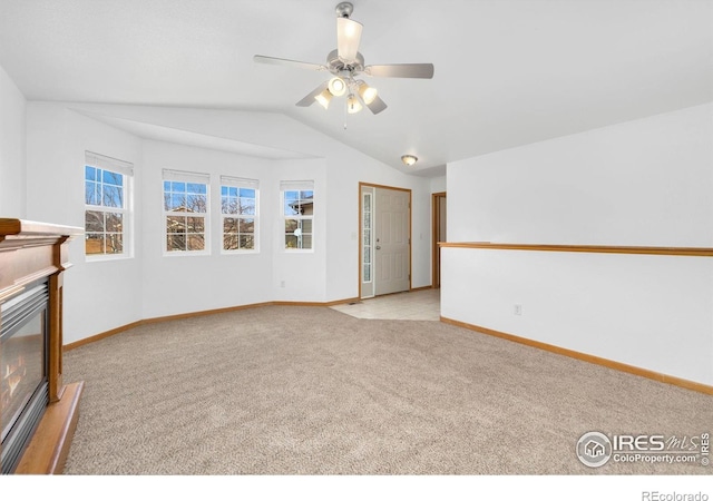 unfurnished living room featuring light carpet, a ceiling fan, a glass covered fireplace, baseboards, and vaulted ceiling