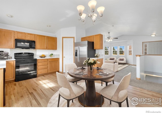 dining area with ceiling fan with notable chandelier, light wood-style floors, and vaulted ceiling