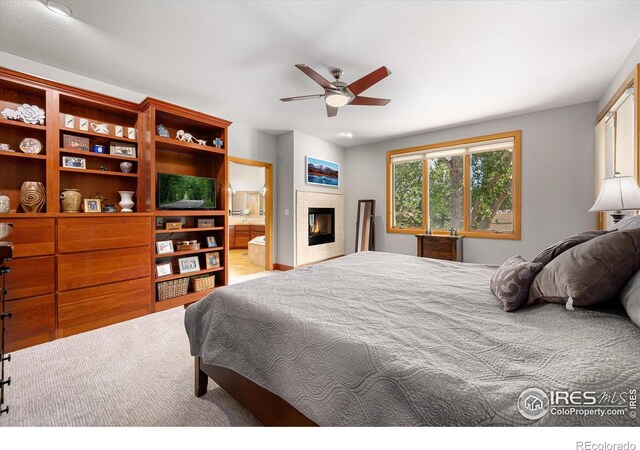 bedroom with ceiling fan, a fireplace, and ensuite bathroom