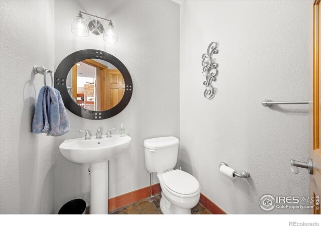 half bath featuring baseboards, a sink, toilet, and tile patterned floors