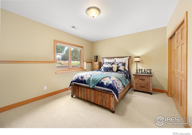 bedroom with a closet, light carpet, visible vents, and baseboards