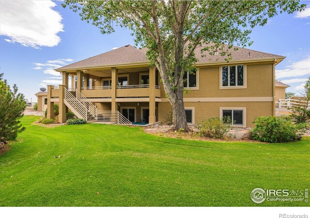 back of house with stairway, a lawn, and stucco siding