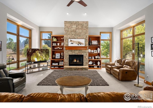 living area featuring lofted ceiling, a fireplace, carpet flooring, and a ceiling fan