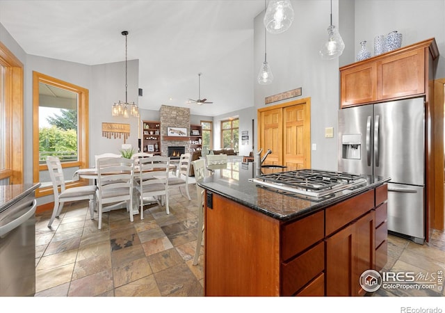 kitchen with dark stone counters, appliances with stainless steel finishes, a fireplace, and stone tile flooring