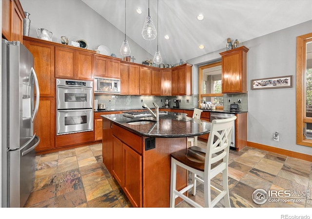 kitchen with brown cabinets, tasteful backsplash, stainless steel appliances, and stone tile flooring