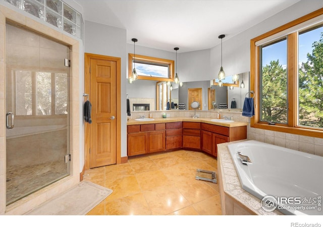 full bathroom featuring double vanity, a garden tub, a shower stall, and a sink