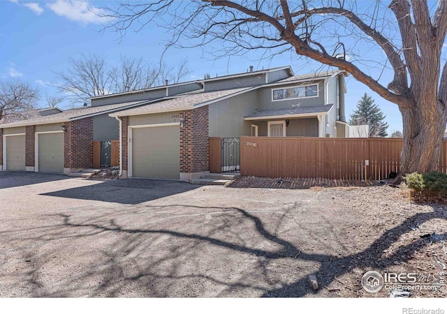 view of front of house with a fenced front yard, brick siding, driveway, and an attached garage