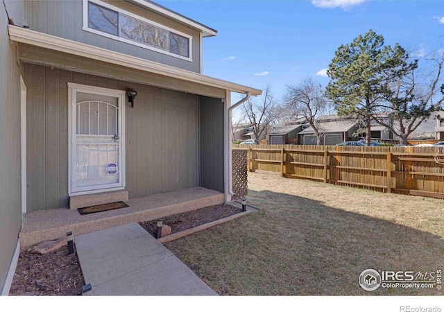 doorway to property with fence and a yard