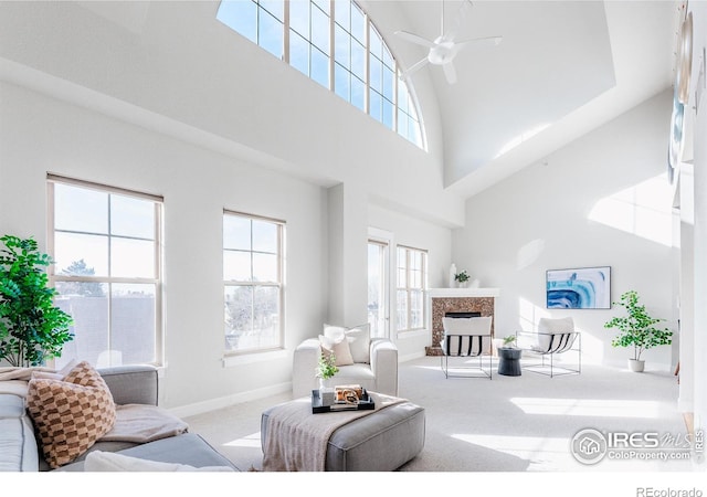 living room with high vaulted ceiling, a tile fireplace, a ceiling fan, baseboards, and carpet