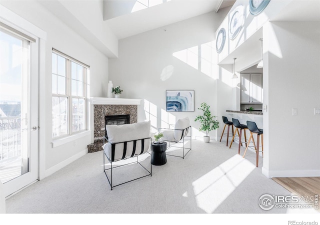 living room with a high ceiling, baseboards, and a fireplace