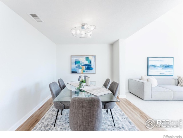 dining area featuring wood finished floors, visible vents, and baseboards