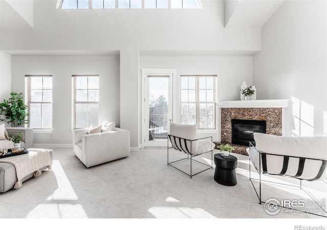 living room with carpet, a fireplace, a towering ceiling, and baseboards