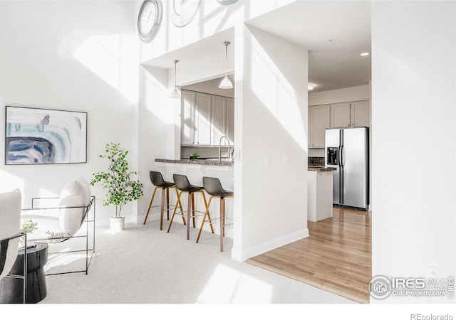 kitchen with gray cabinetry, baseboards, a sink, and stainless steel fridge with ice dispenser