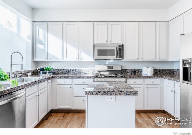 kitchen featuring tile countertops, stainless steel appliances, light wood-style floors, white cabinetry, and a sink