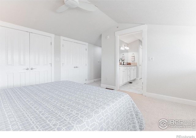 bedroom featuring light carpet, baseboards, ceiling fan, vaulted ceiling, and multiple closets