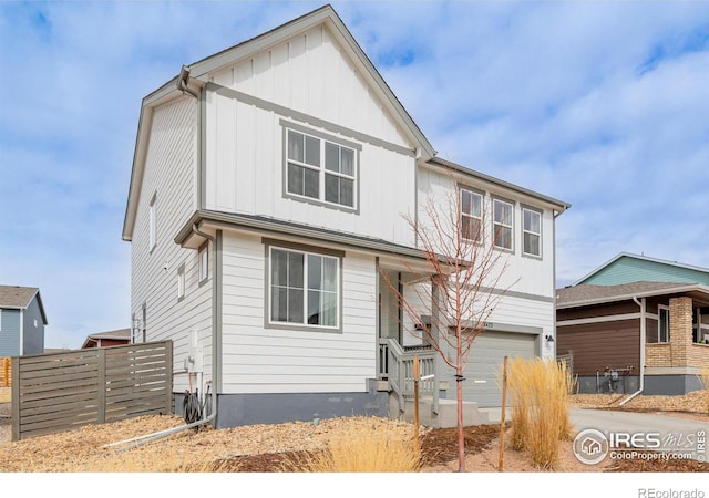 view of front of property with an attached garage, driveway, fence, and board and batten siding