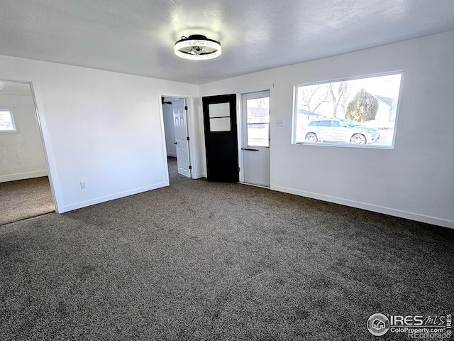 foyer featuring a healthy amount of sunlight, baseboards, and dark carpet