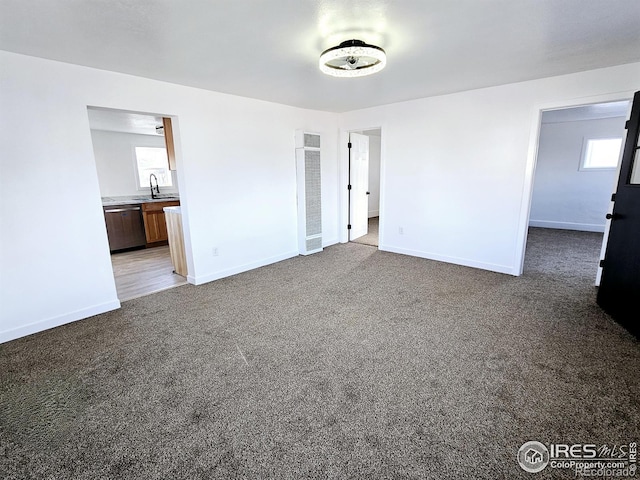 unfurnished bedroom featuring dark carpet, a sink, and baseboards