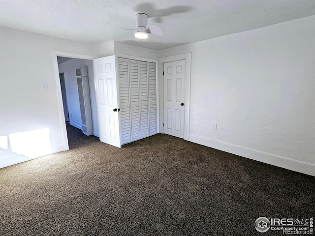 unfurnished bedroom with baseboards, dark carpet, ceiling fan, and a closet