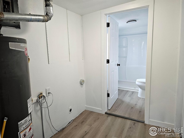 clothes washing area with light wood-style flooring and water heater