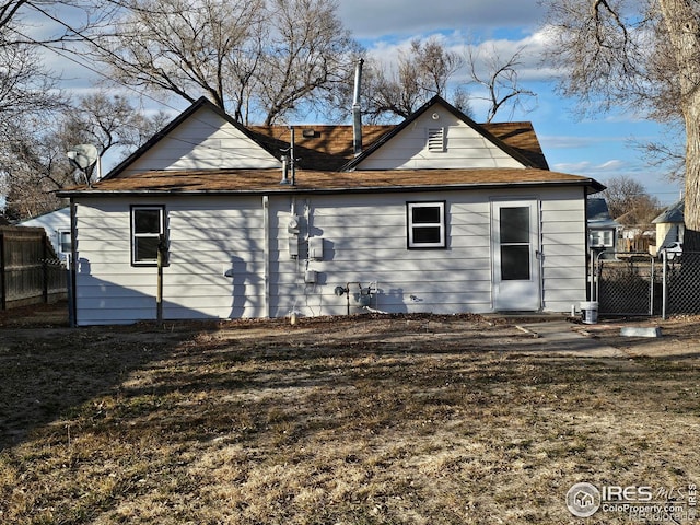 back of property with a gate and fence