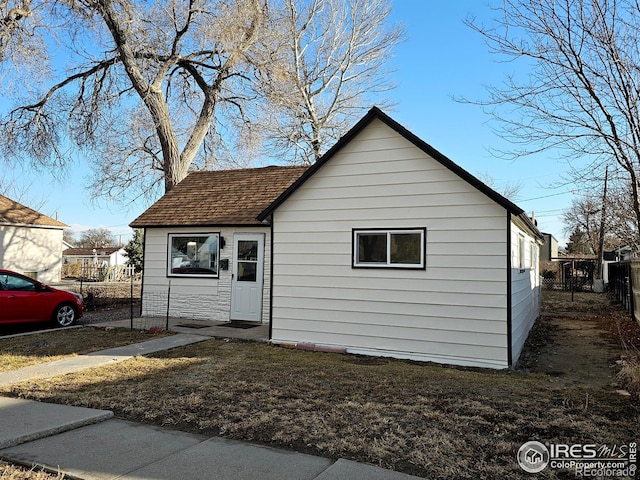 view of property exterior with a shingled roof and fence