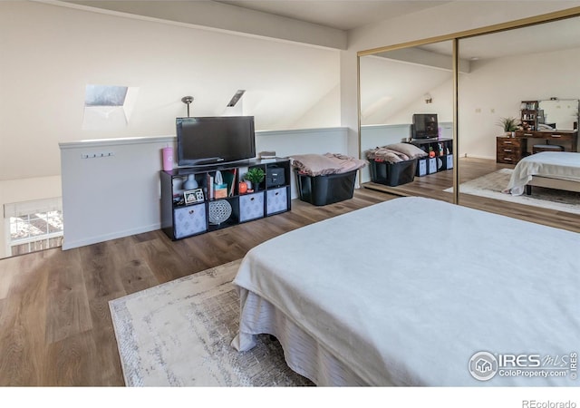 bedroom with vaulted ceiling with beams, a closet, and wood finished floors