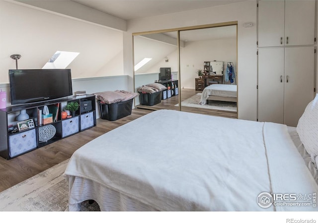 bedroom with a closet, lofted ceiling with beams, and wood finished floors