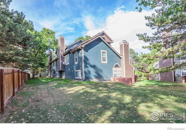 back of house with a chimney, fence, and a yard