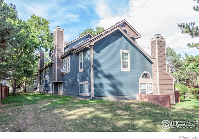 back of property with a chimney and a yard