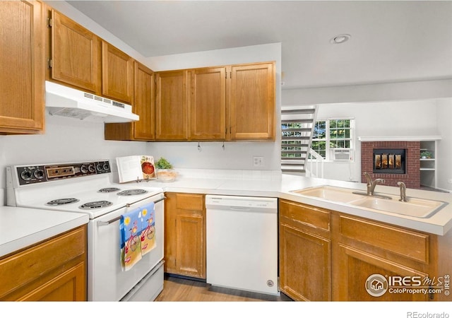 3565 Windmill Dr Unit 5, Fort Collins, CO 80526 - kitchen with white appliances, under cabinet range hood, a sink, a peninsula, and a brick fireplace