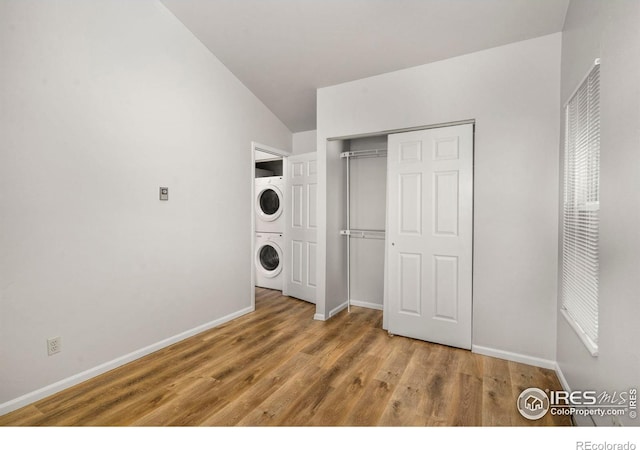 3565 Windmill Dr Unit 5, Fort Collins, CO 80526 - unfurnished bedroom featuring stacked washing machine and dryer, wood finished floors, baseboards, a closet, and lofted ceiling