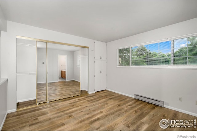 3565 Windmill Dr Unit 5, Fort Collins, CO 80526 - unfurnished bedroom featuring a baseboard heating unit, light wood finished floors, baseboards, and a closet