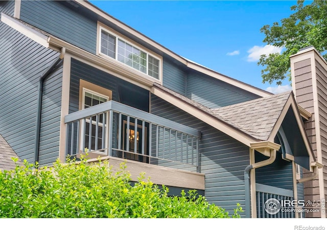 3565 Windmill Dr Unit 5, Fort Collins, CO 80526 - view of side of home featuring a shingled roof, a chimney, and a balcony